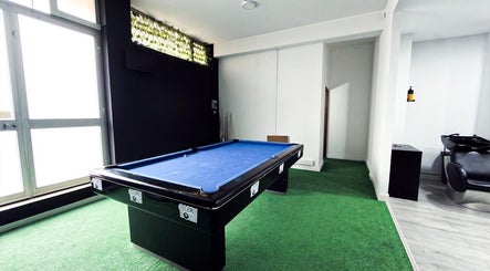 Sala de lazer em Barbearia Maia, Braga, PT, com mesa de bilhar e cadeiras de barbeiro modernas.