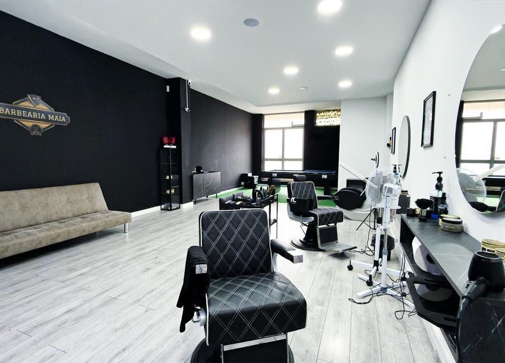 Interior moderno da Barbearia Maia em Braga, PT, com cadeiras luxuosas e decoração estilizada.