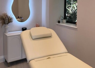 Relaxing treatment room at Exquisique Nails & Beauty, Epsom, England, GB with ambient lighting and a plush bed.
