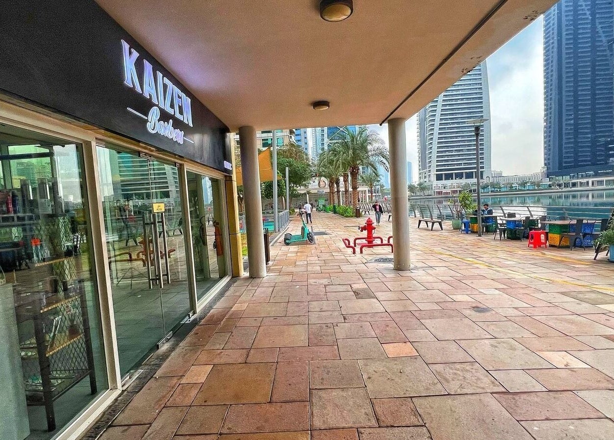 Scenic exterior of Kaizen Barbershop in Dubai, Dubai, AE, with a view of the skyline and a waterfront pathway.