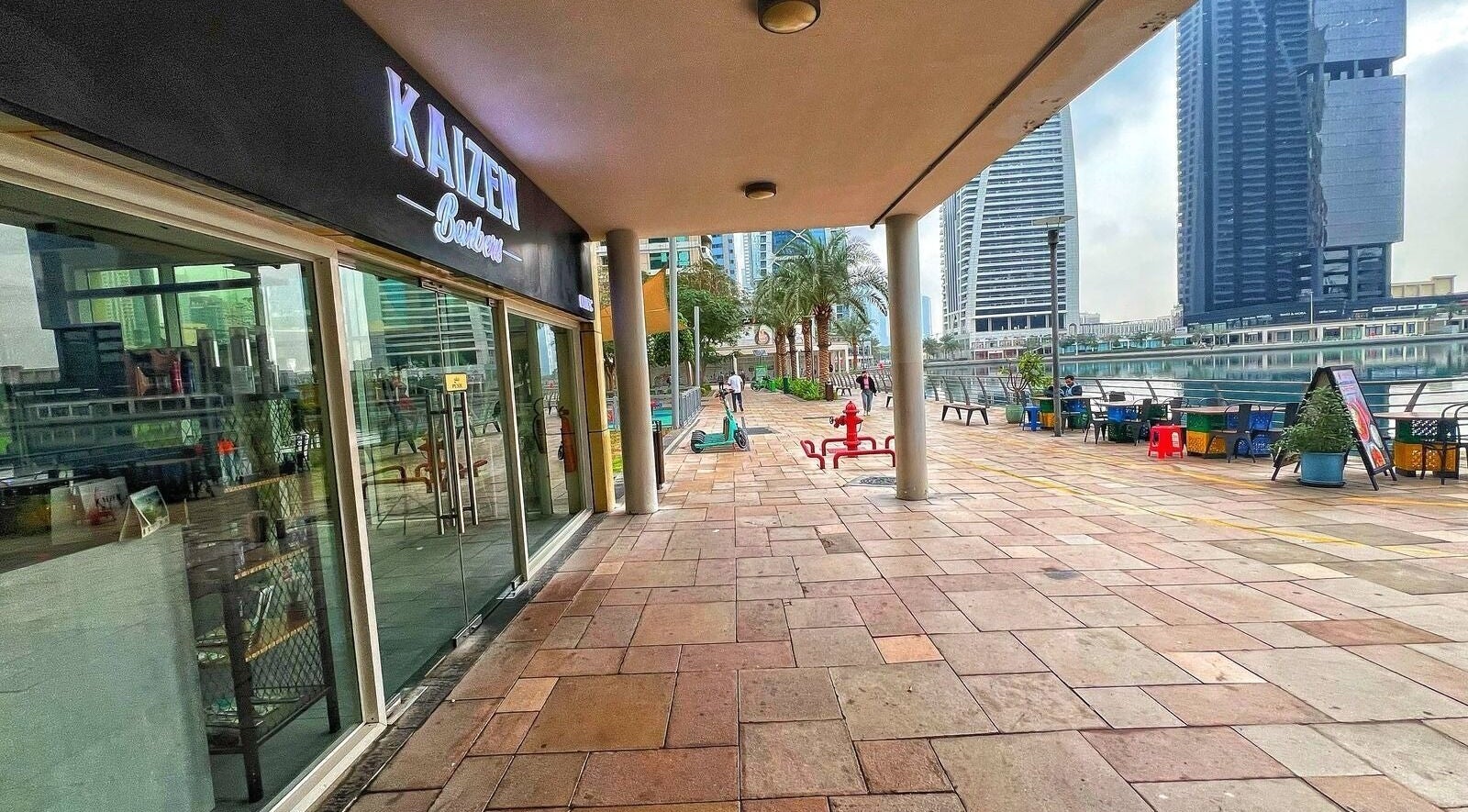 Scenic exterior of Kaizen Barbershop in Dubai, Dubai, AE, with a view of the skyline and a waterfront pathway.