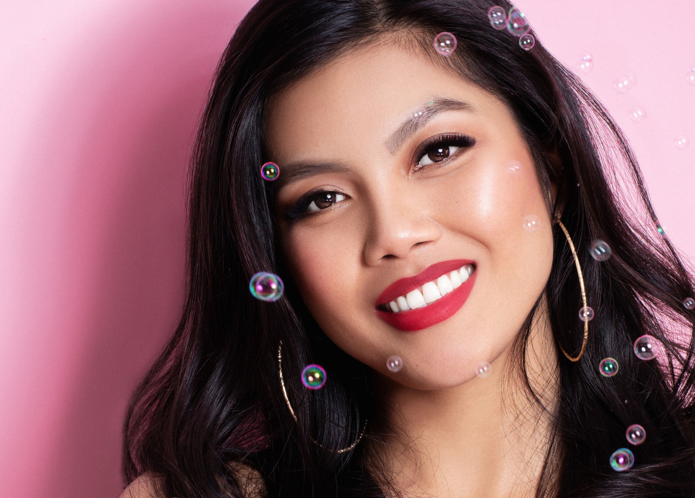 Smiling woman with bright makeup and earrings at Posh Deluxe, Mount Pleasant, Western Australia, AU.