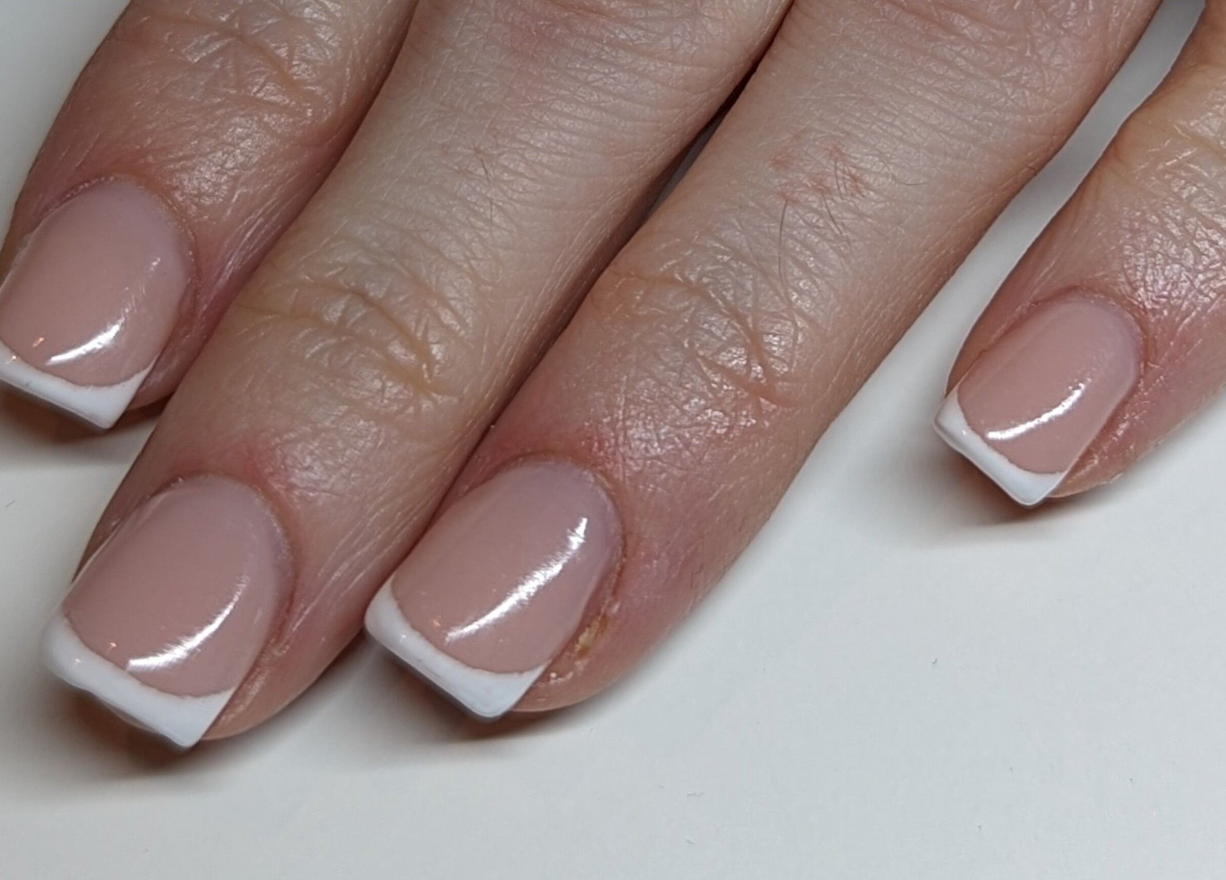 Classic French manicure at Kmac Studio, Dunbar, Scotland, GB. Pink nails with white tips, elegant and glossy.
