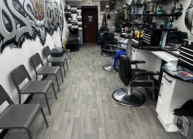 Modern interior of Boss Kutz Barbers in Birmingham, England, GB with chairs, mirrors, and graffiti wall art.