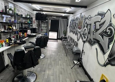Interior of Boss Kutz Barbers in Birmingham, England, GB, featuring stylish chairs and vibrant graffiti art.