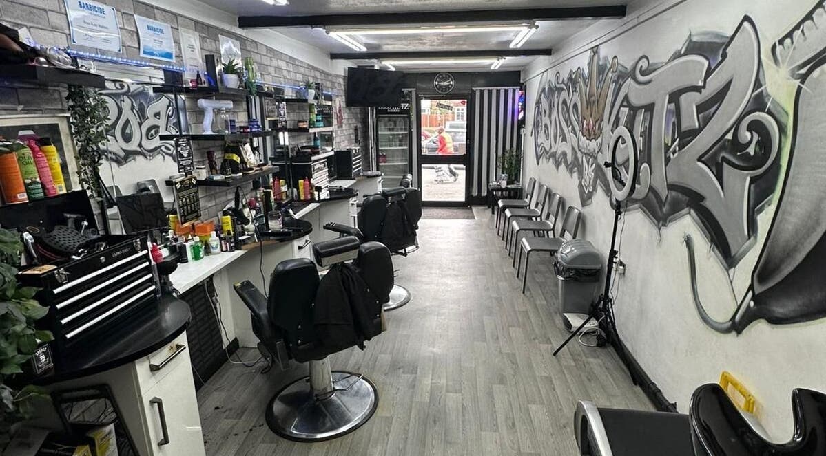 Modern interior of Boss Kutz Barbers in Birmingham, England, GB showcasing stylish chairs and graffiti art.