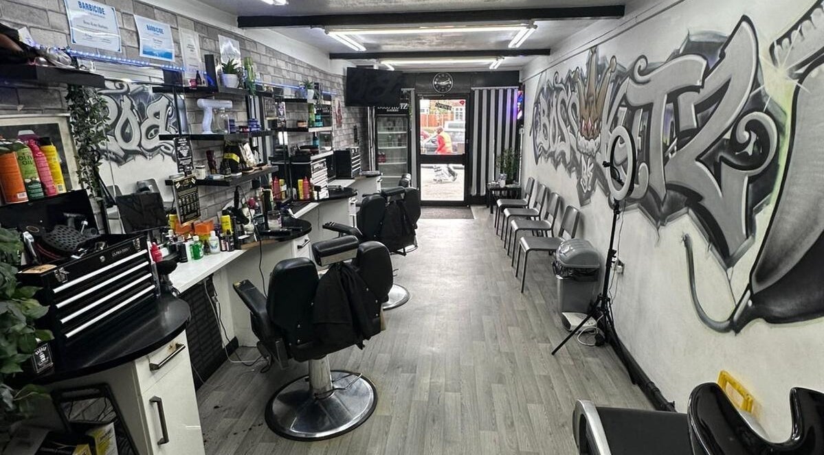Interior of Boss Kutz Barbers in Birmingham, England, GB showcasing stylish chairs, graffiti art, and grooming tools.