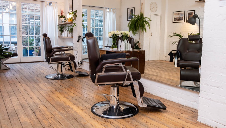 Interior of Breathe Barbers, London, England, GB with stylish barber chairs and wooden floors.
