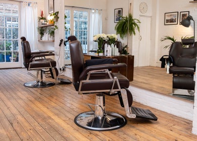 Interior of Breathe Barbers, London, England, GB with stylish barber chairs and wooden floors.