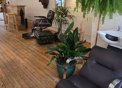 Modern barbershop interior at Breathe Barbers, London, England, GB, featuring stylish chairs and lush greenery.