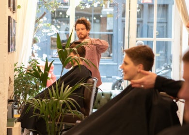 Skilled barber at Breathe Barbers, London, England, crafting stylish haircuts amidst a modern, inviting interior.