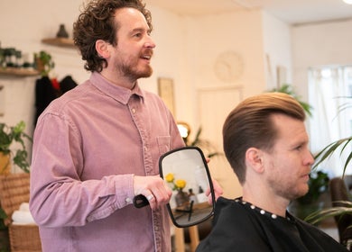 Barber shows haircut in mirror at Breathe Barbers, London, England, GB.