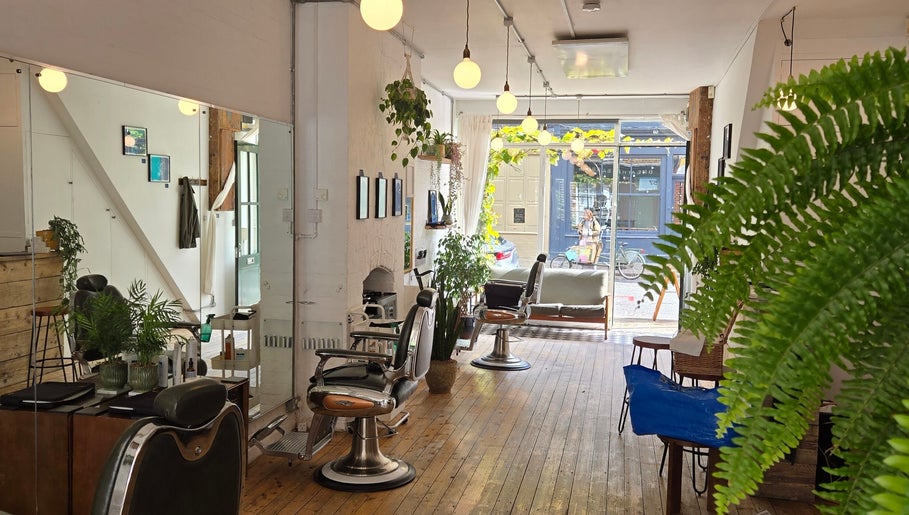 Sleek interior of Breathe Barbers in London, England, GB with stylish barber chairs and bright plants.