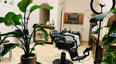 Interieur van Dakhil Kapper in Turnhout, Vlaams Gewest, BE, met moderne kappersstoel en stijlvolle planten.