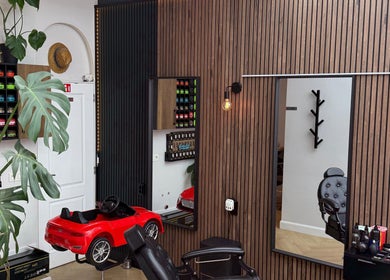 Interieur van Dakhil kapper in Turnhout, Vlaams Gewest, BE met modern houten wandontwerp en kinderkappersstoel.