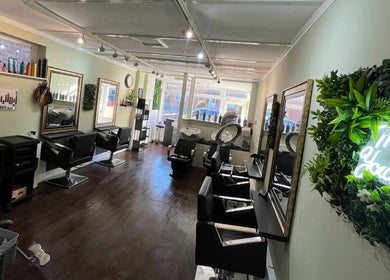 Modern salon interior of Hair by Faye in Colchester, England, GB with stylish mirrors and neon sign.