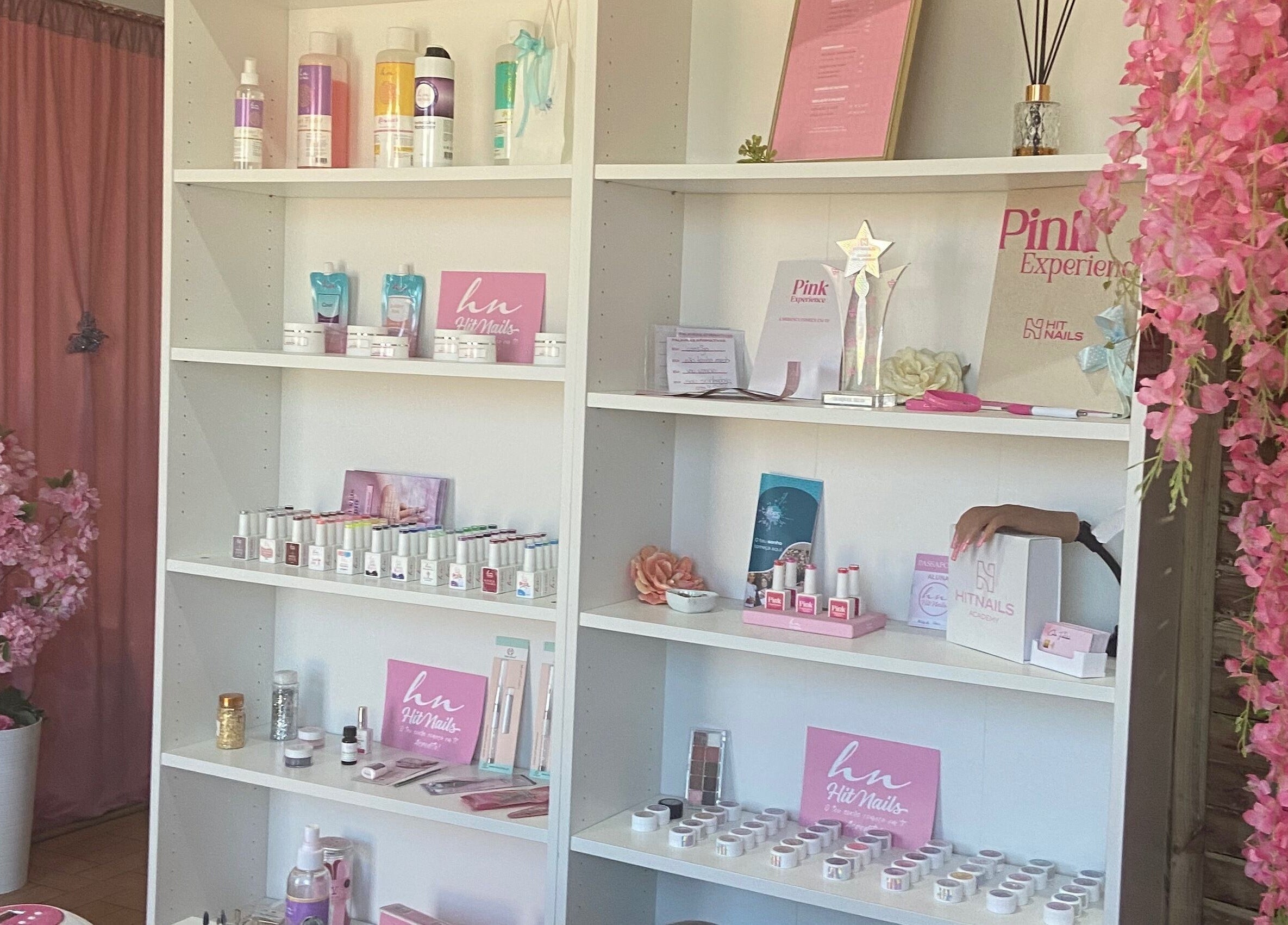 Prateleiras de produtos de beleza do RaquelReistudio em Aveiro, Aveiro, PT, com decorações florais rosa.