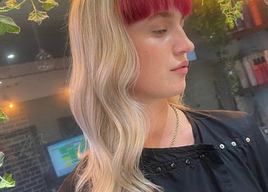 Elegant hairstyle at Hair By David in East Kilbride, Scotland, GB, showcasing blonde waves with pink fringe.