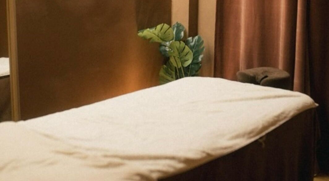 Table de massage à Studio by Holy, Paris, Île-de-france, FR, avec rideaux marrons et feuillage apaisant.