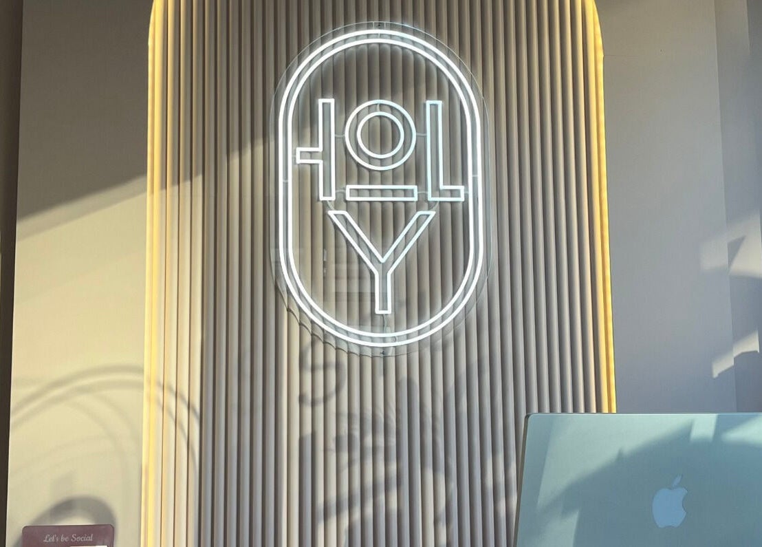 Logo lumineux de Studio by Holy à Paris, Île-de-France, FR, sur fond orné de rayures verticales.