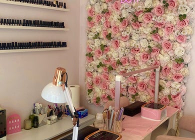 Nail salon workspace at Glow it, Limenas Chersonisou, GR, with floral wall and organized nail polish display.