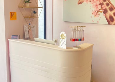 Reception area at Glow it, Limenas Chersonisou, GR featuring elegant decor and a vibrant wall art piece.