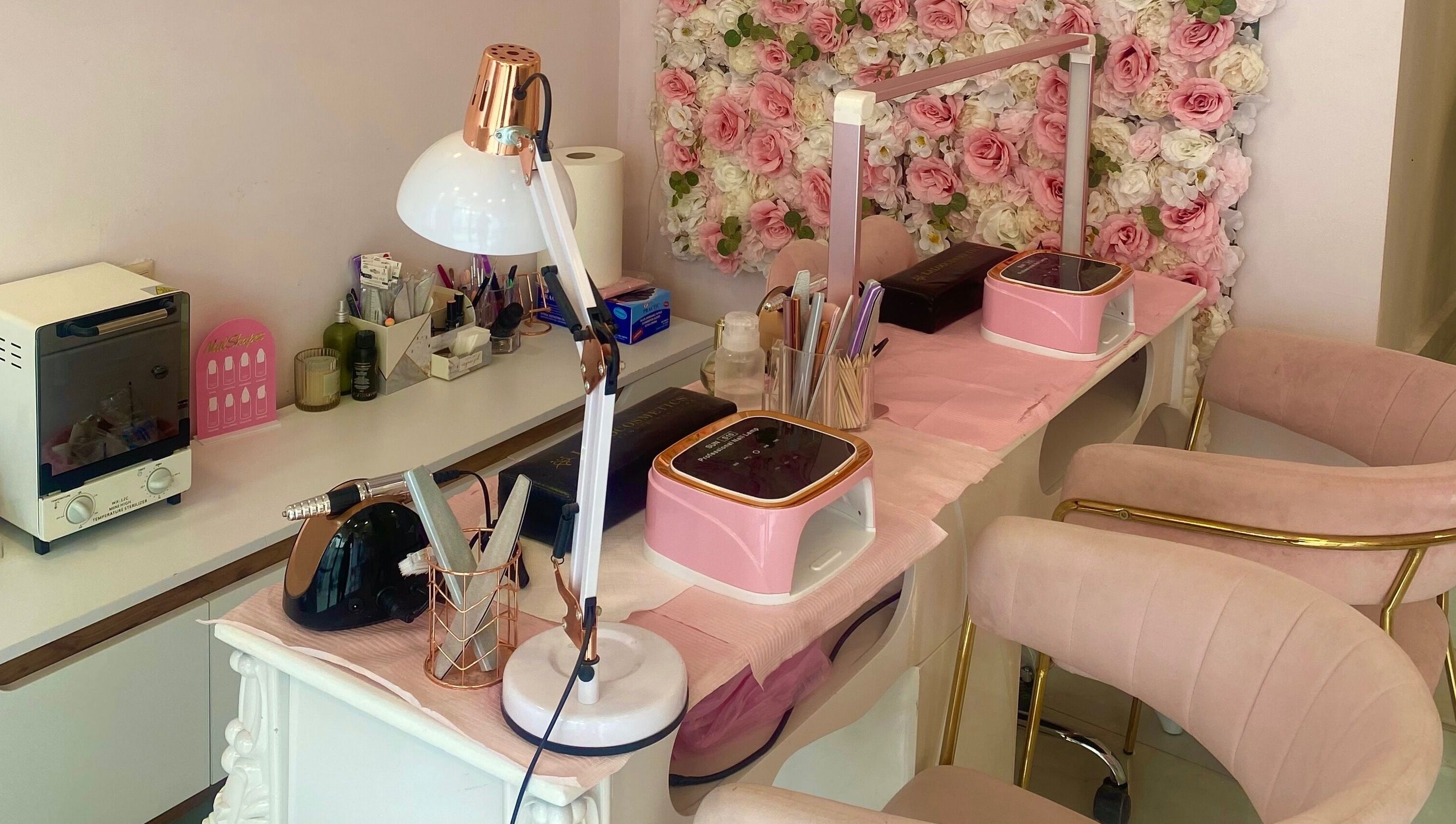 Stylish manicure station at Glow it, Limenas Chersonisou, GR with pink decor and floral backdrop.