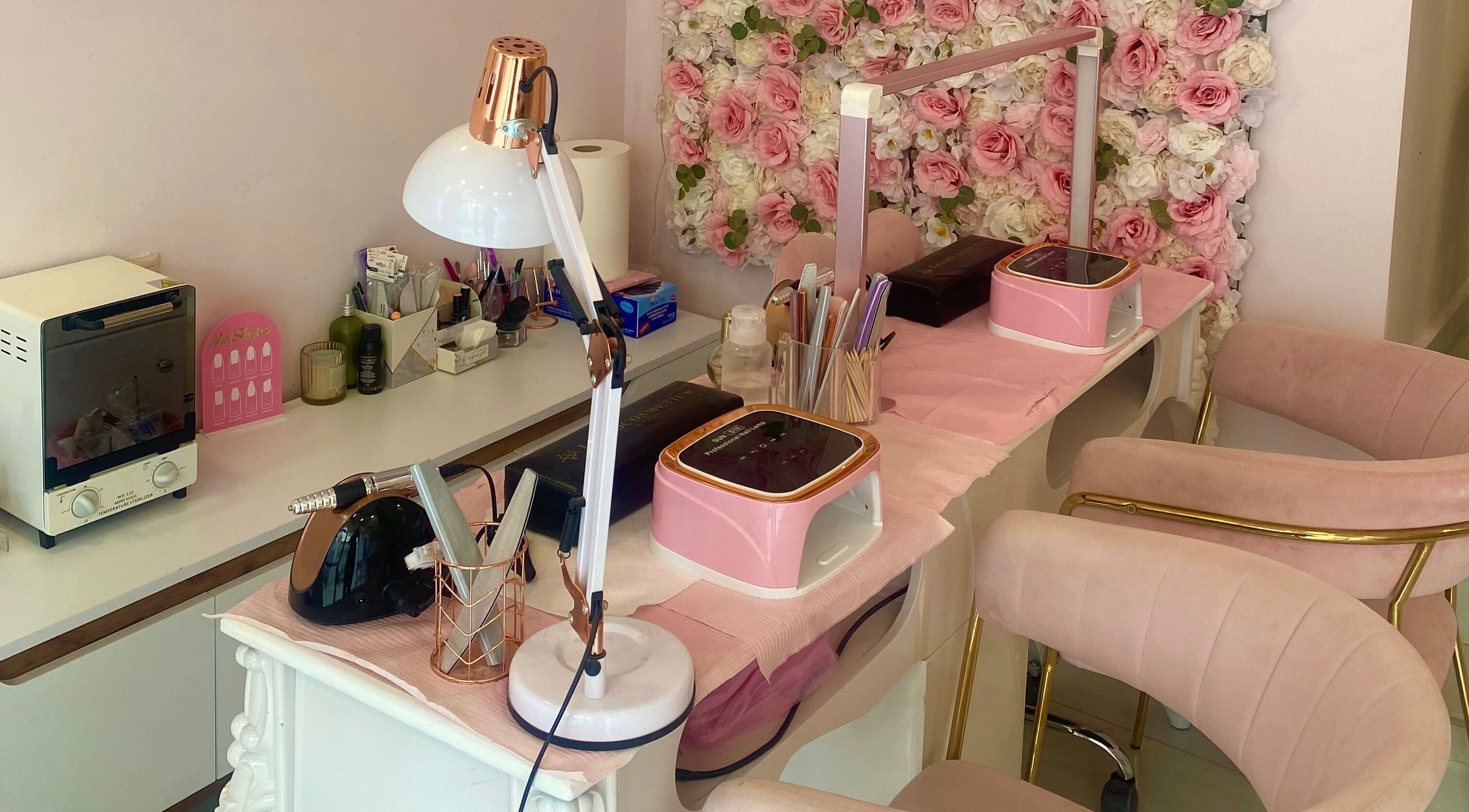 Stylish manicure station at Glow it, Limenas Chersonisou, GR with pink decor and floral backdrop.