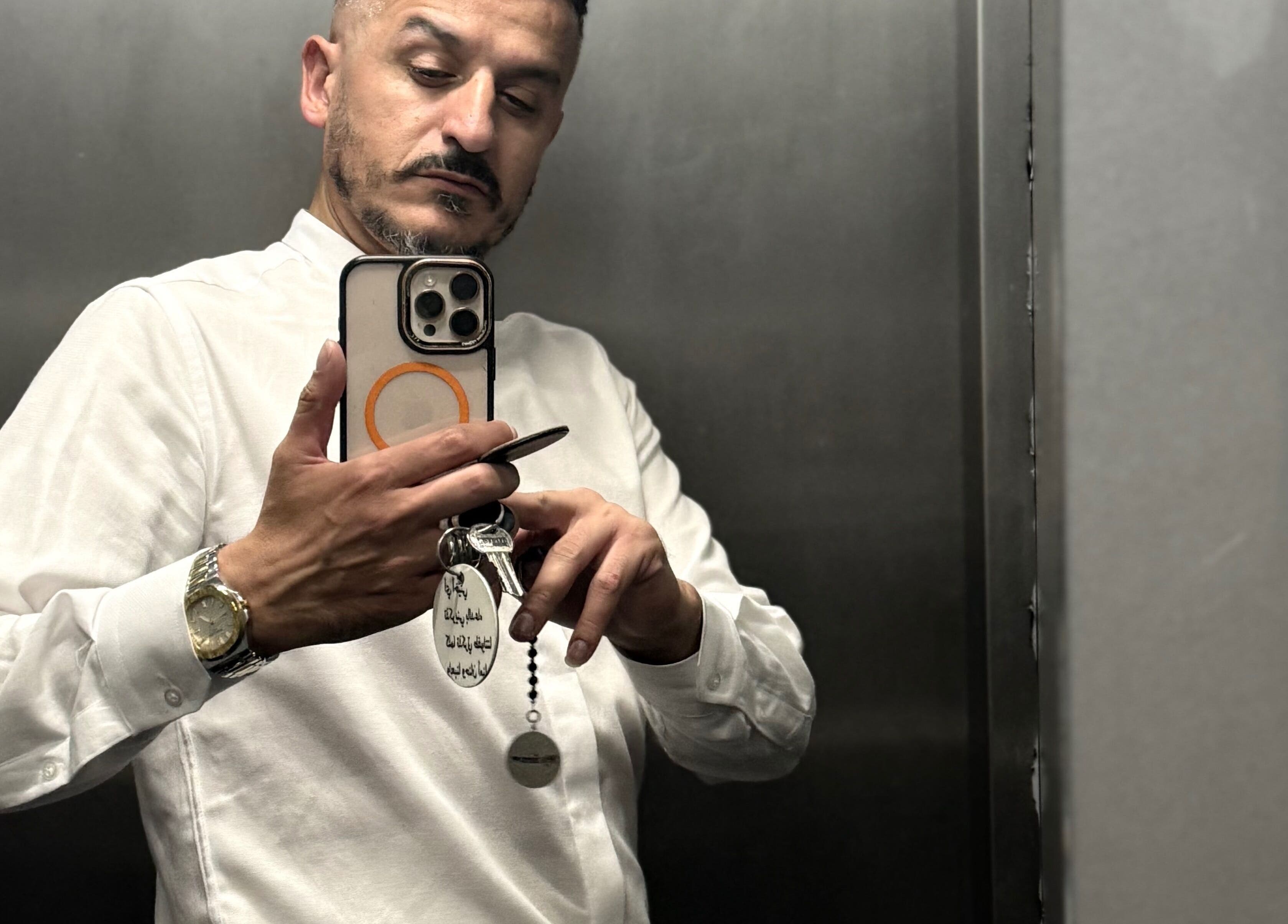 رجل يحمل هاتفًا في مصعد، يرتدي قميصًا أبيض في شعر و ذقن Hair and Beard שער ו זקן, ירושלים, ירושלים, IL.