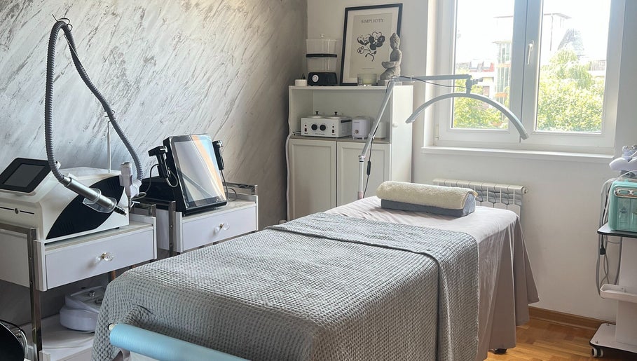 Serene treatment room at Adore Me Beauty Studio, Beograd, RS, with equipment and a cozy bed.