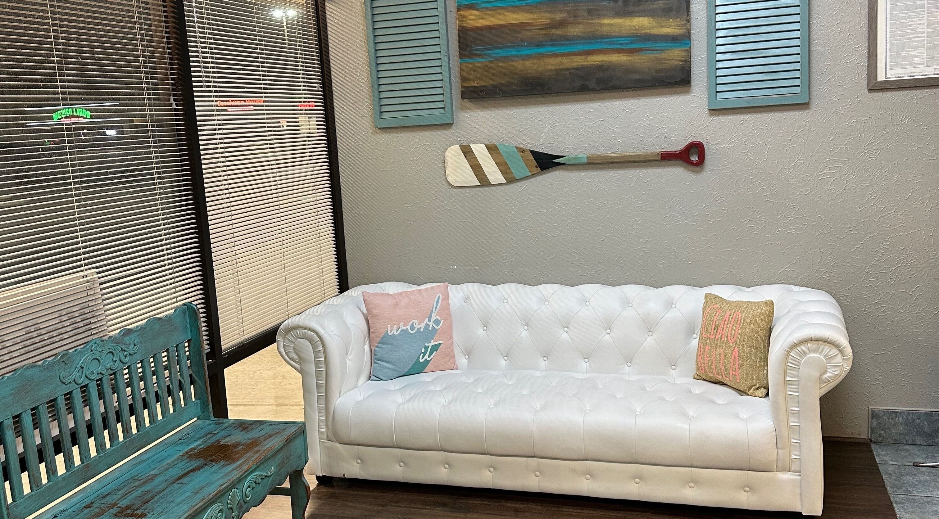 Inviting lounge area with white tufted sofa at The Wave Salon, Broken Arrow, Oklahoma, US.