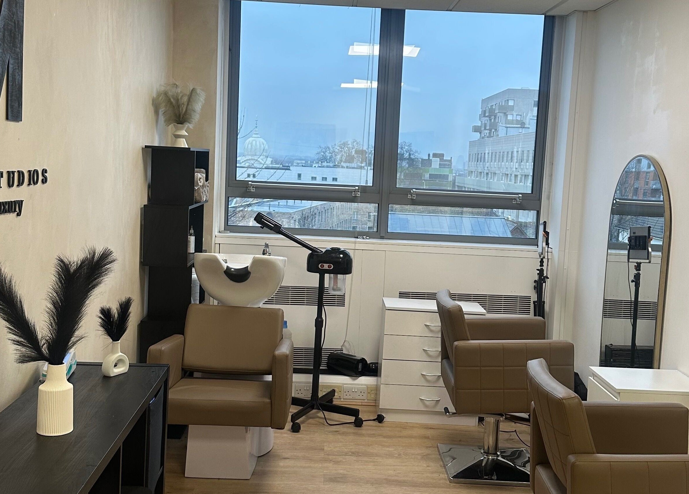 M London Studios in Barking, England, GB. Modern beauty setup with chairs, mirrors, and large window view.