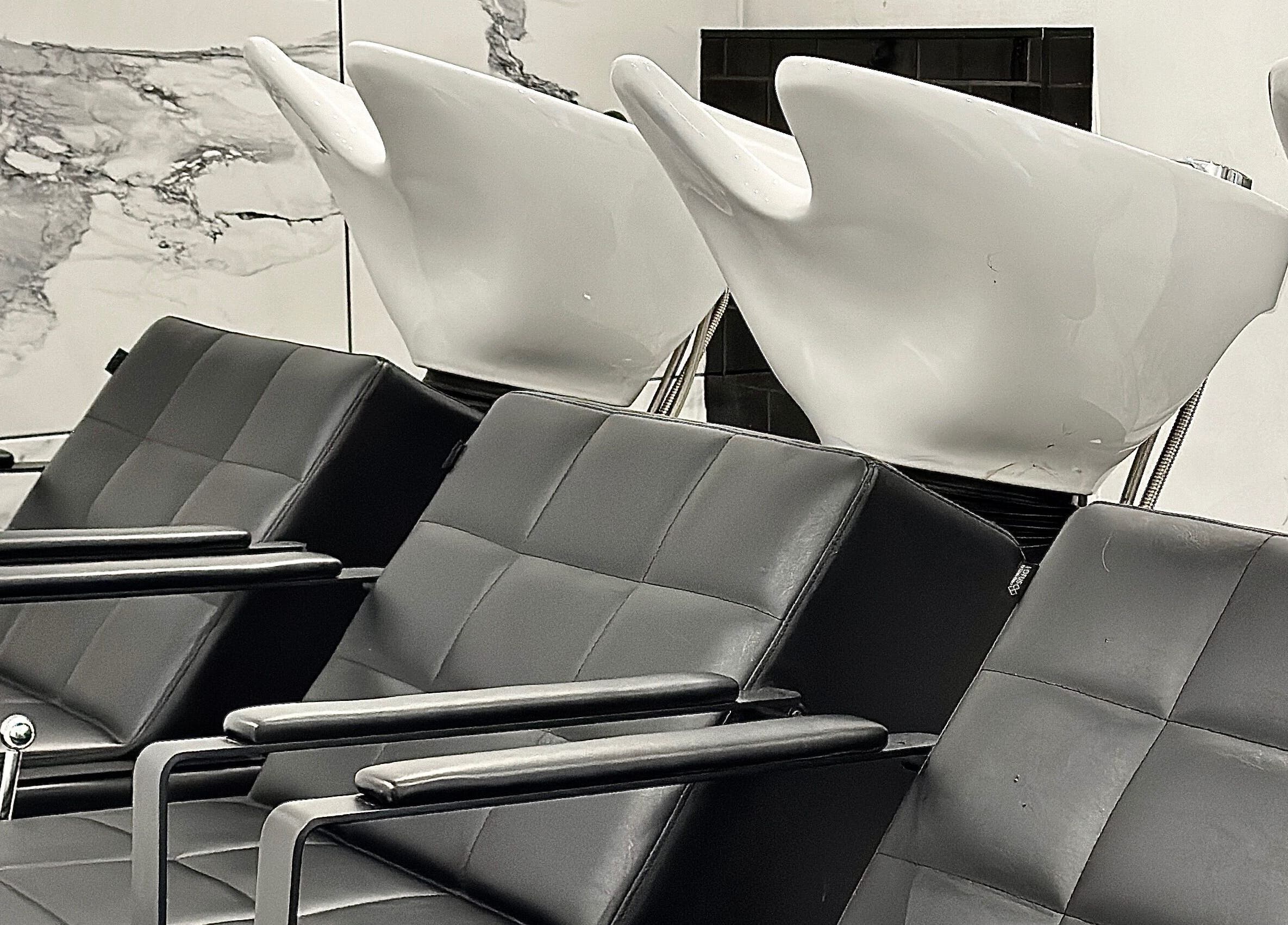 Modern wash stations at SHADE ANDOVER, Andover, England, GB. Sleek black seating with white basins.