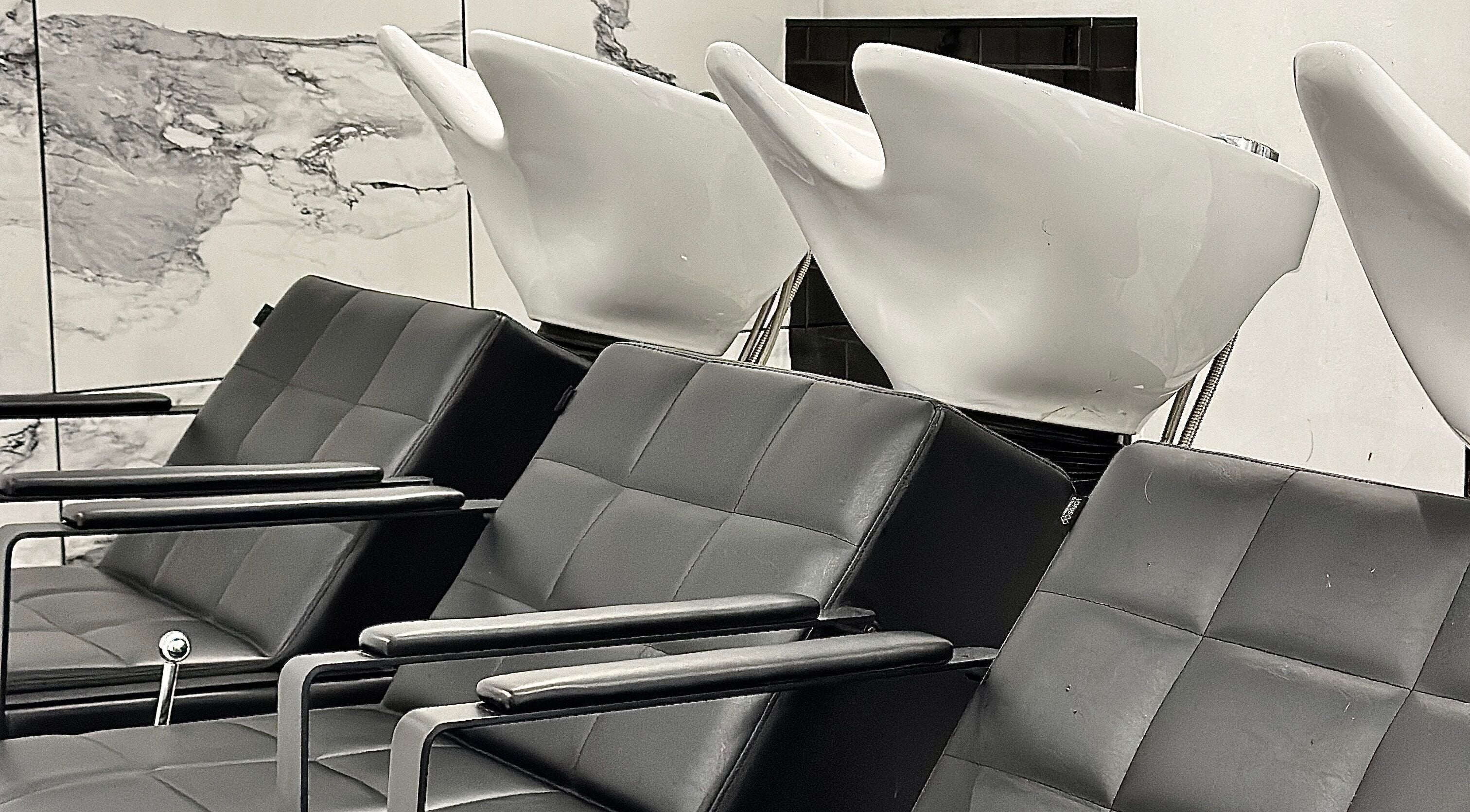 Modern wash stations at SHADE ANDOVER, Andover, England, GB. Sleek black seating with white basins.