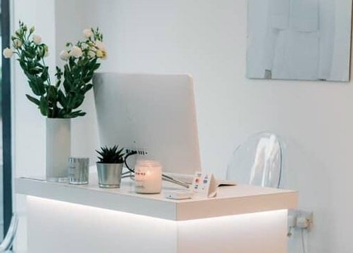 Modern reception desk at SHADE ANDOVER, Andover, England, GB with flowers and a lit candle.