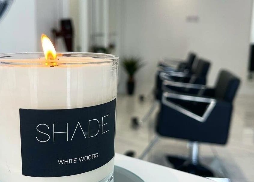 A lit candle adds a touch of calm in SHADE ANDOVER, Andover, England, GB, modern salon setting with stylish chairs.
