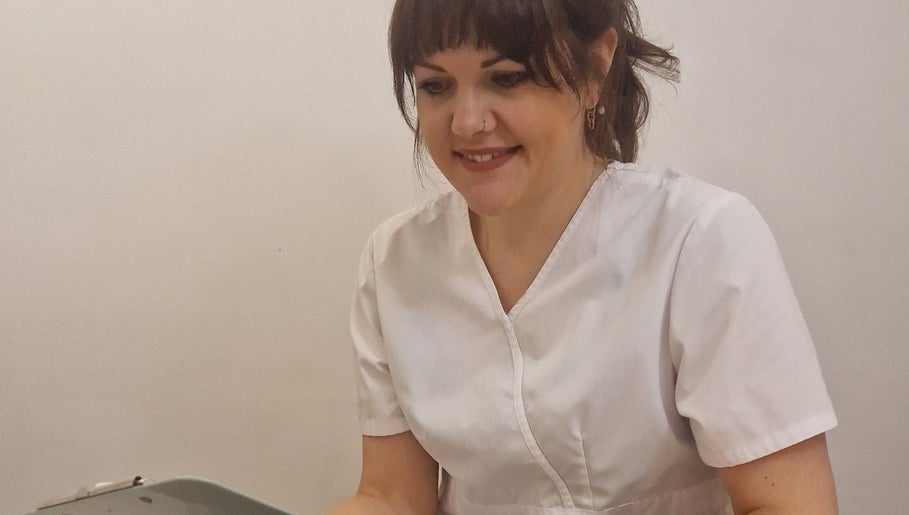 Smiling therapist at Katie Betty Laser & Aesthetics, Portsmouth, England, GB in a white uniform.