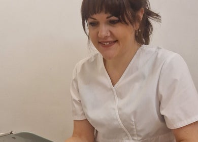 Smiling therapist at Katie Betty Laser & Aesthetics, Portsmouth, England, GB in a white uniform.