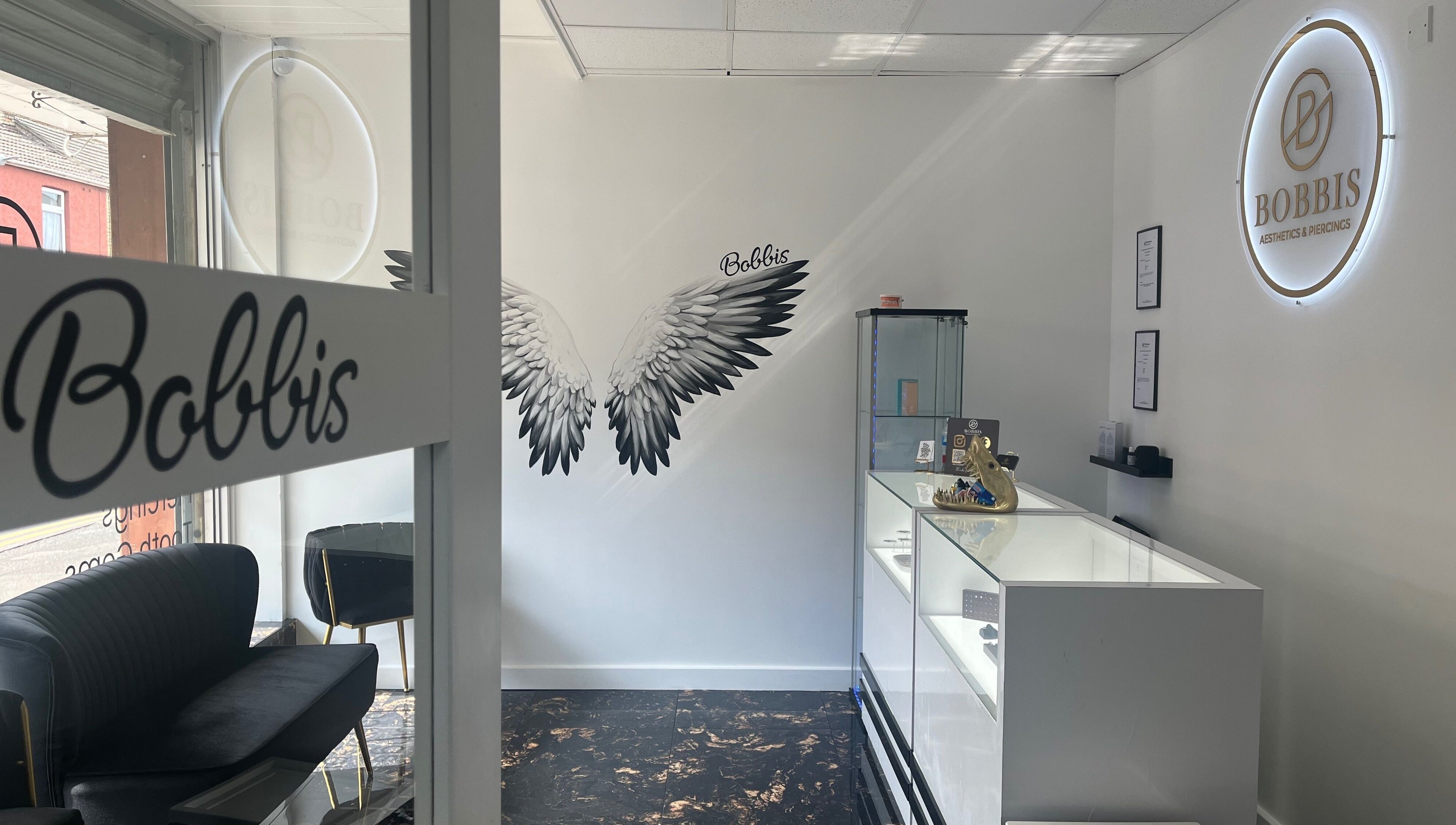 Interior of Bobbi's Aesthetics & Piercing in Bletchley, England, featuring chic seating and modern design.