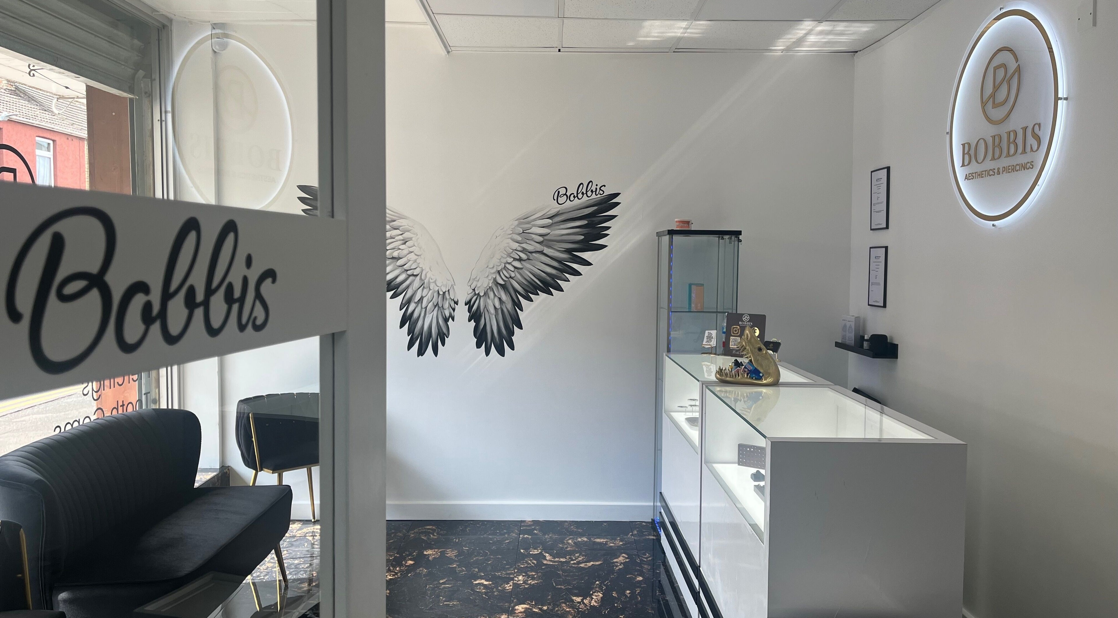 Interior of Bobbi's Aesthetics & Piercing in Bletchley, England, featuring chic seating and modern design.