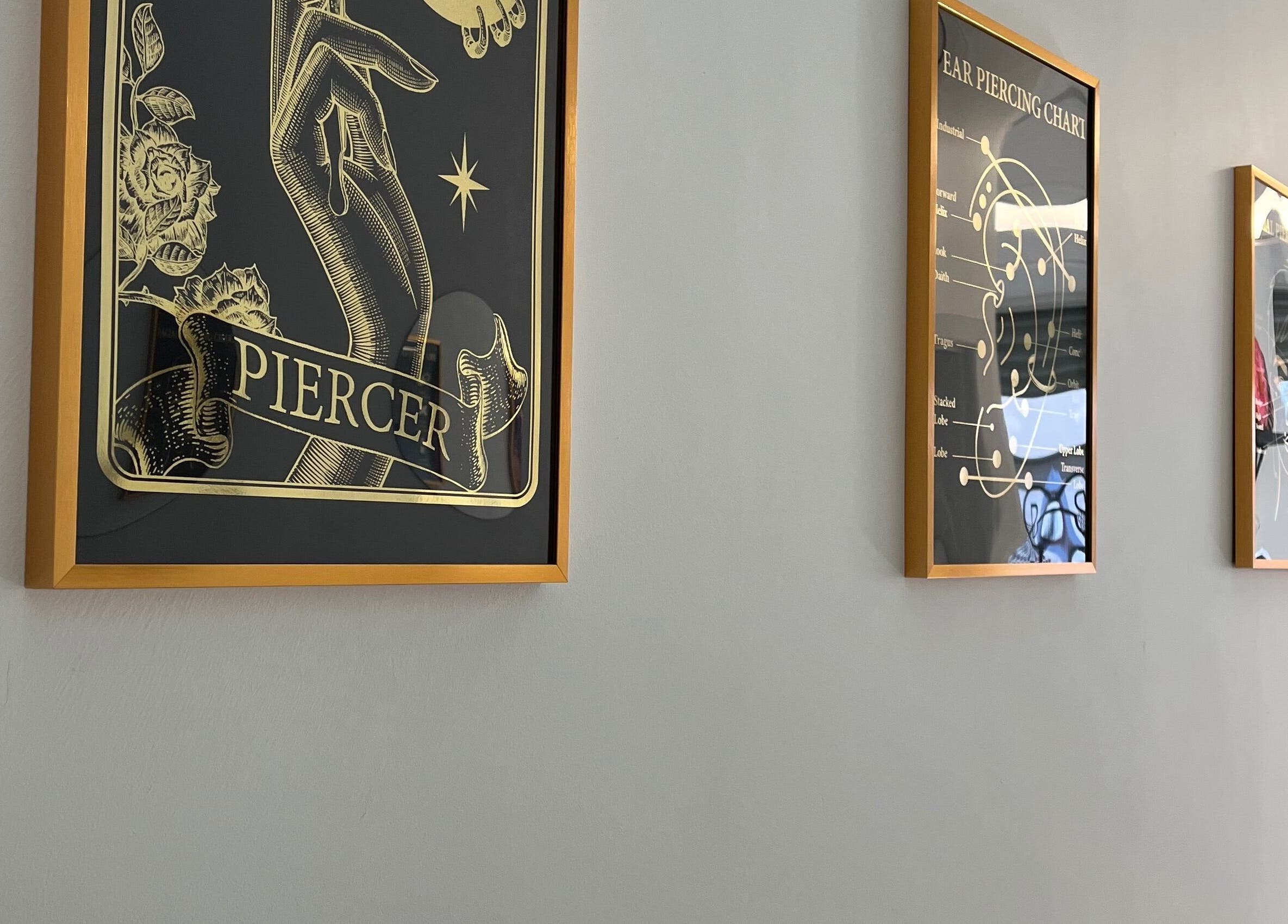 Framed piercing art lining a wall at Bobbi's Aesthetics & Piercing, Bletchley, England, GB.