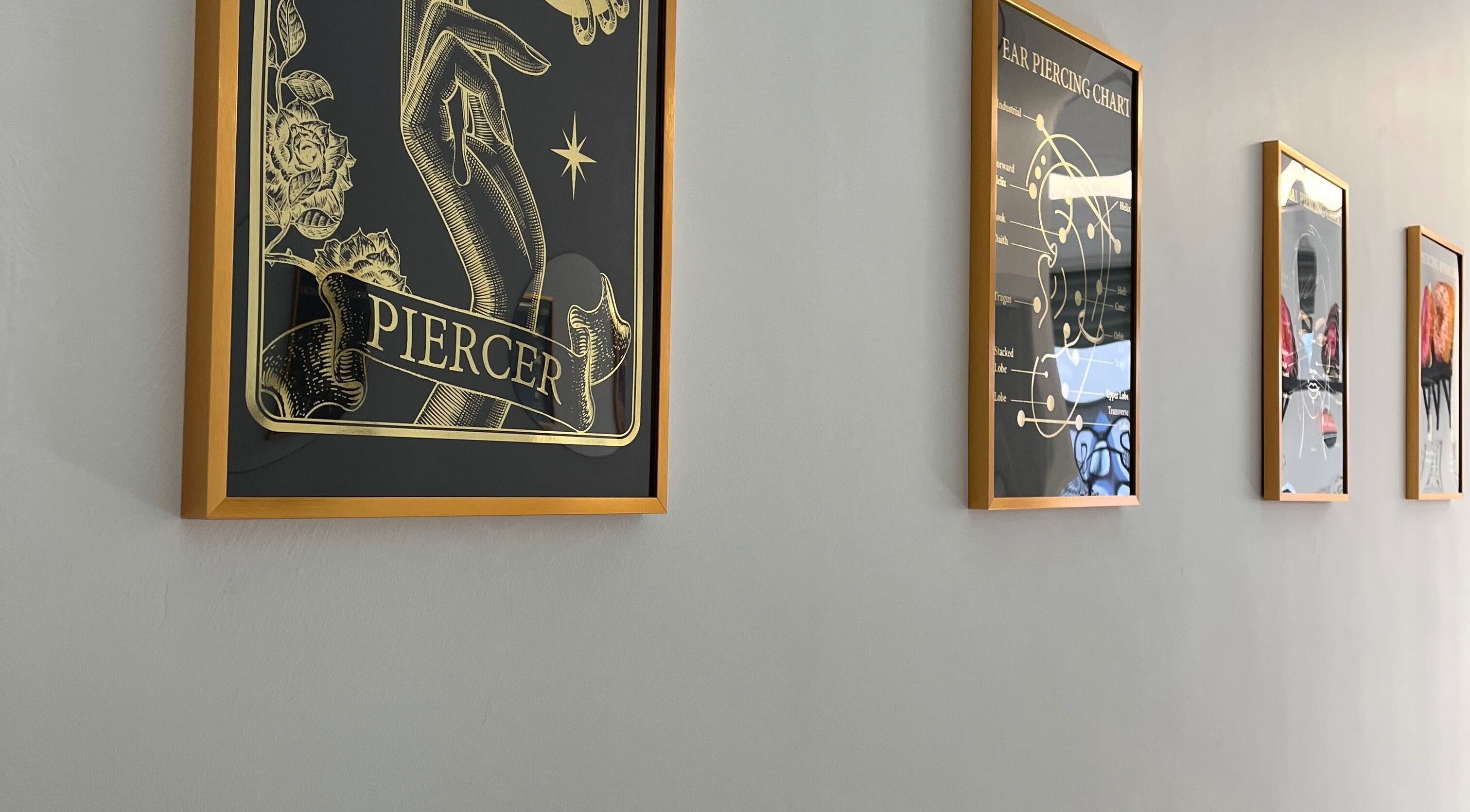 Framed piercing art lining a wall at Bobbi's Aesthetics & Piercing, Bletchley, England, GB.
