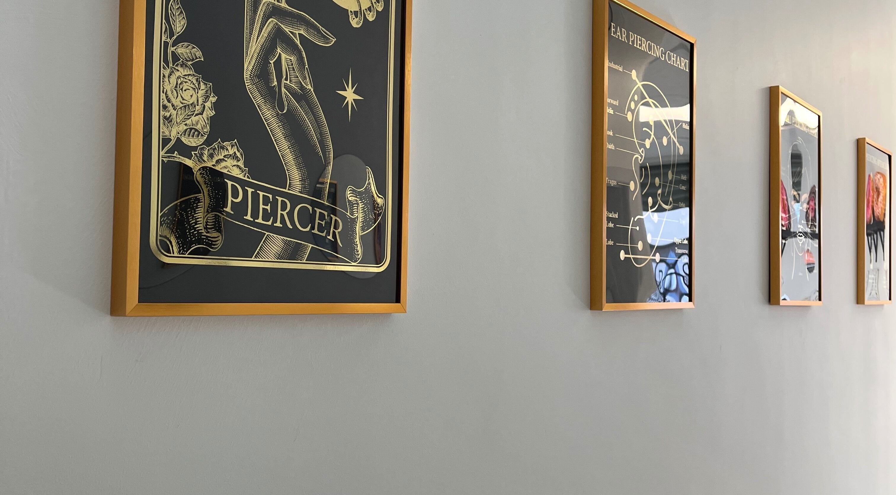 Framed piercing art lining a wall at Bobbi's Aesthetics & Piercing, Bletchley, England, GB.