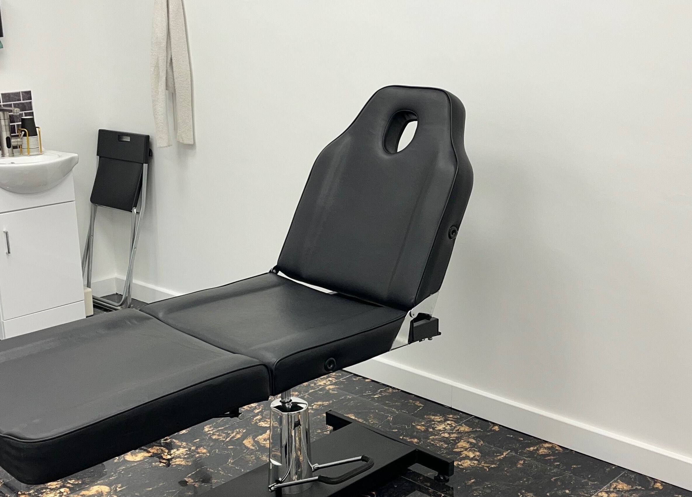 Modern treatment room at Bobbi's Aesthetics & Piercing in Bletchley, England, GB, featuring a sleek black chair.