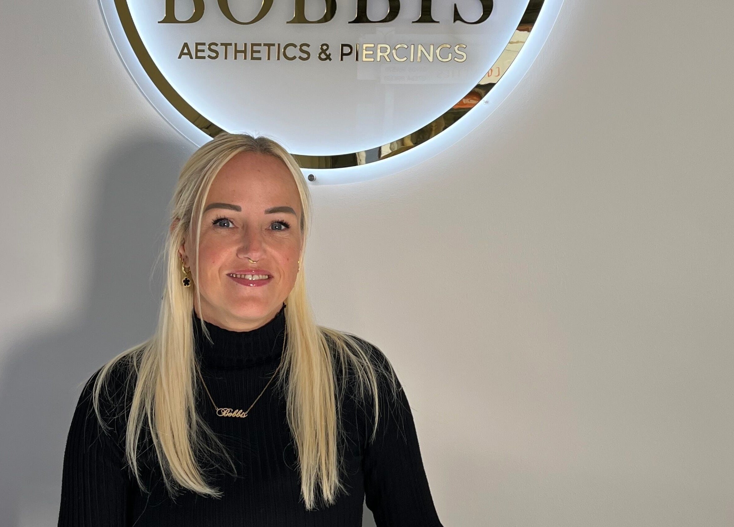 Welcoming staff at Bobbi's Aesthetics & Piercing, Bletchley, England, GB, under chic logo signage.