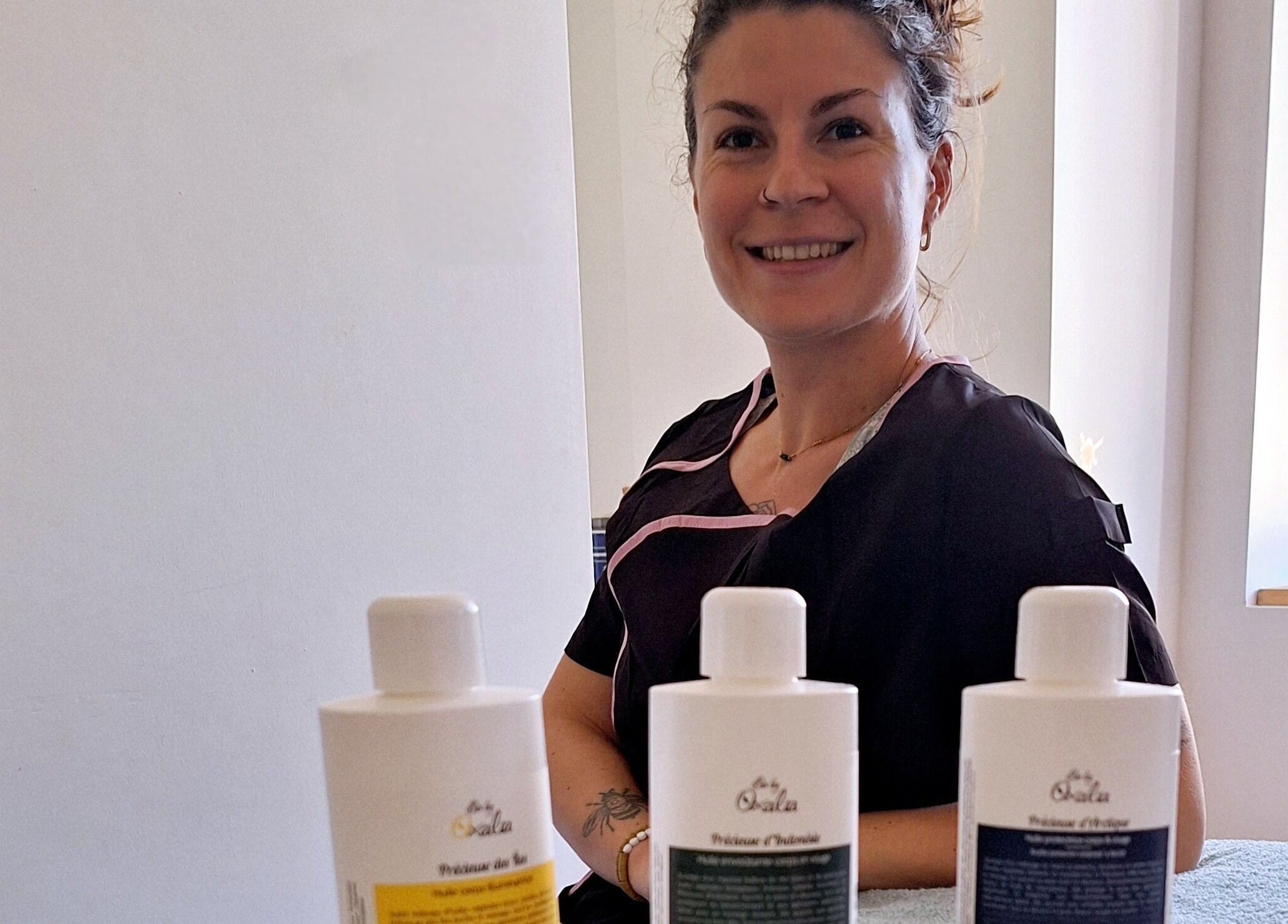 Une esthéticienne souriante à Adansonia Serenity avec des produits de soin, Saint-maurice-en-gourgois, Auvergne-rhône-alpes, FR.