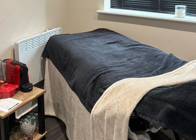 Cozy spa room at BareFaced Beauty by Charlie in Helsby, England, GB, featuring a comfortable massage table and warm decor.