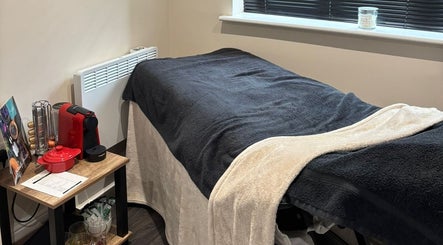 Cozy spa room at BareFaced Beauty by Charlie in Helsby, England, GB, featuring a comfortable massage table and warm decor.