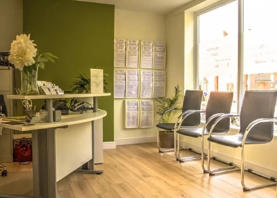 Bright reception at Crystal Clear Hearing, Burton Upon Trent, England with modern chairs and green decor.