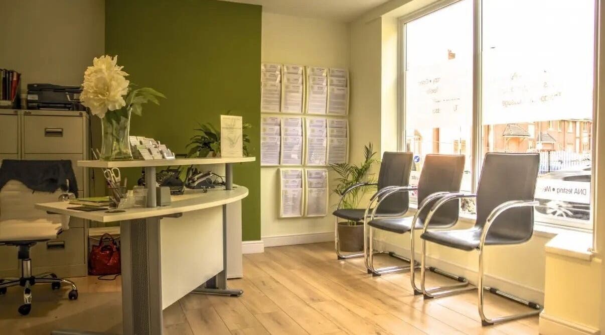 Bright reception at Crystal Clear Hearing, Burton Upon Trent, England with modern chairs and green decor.